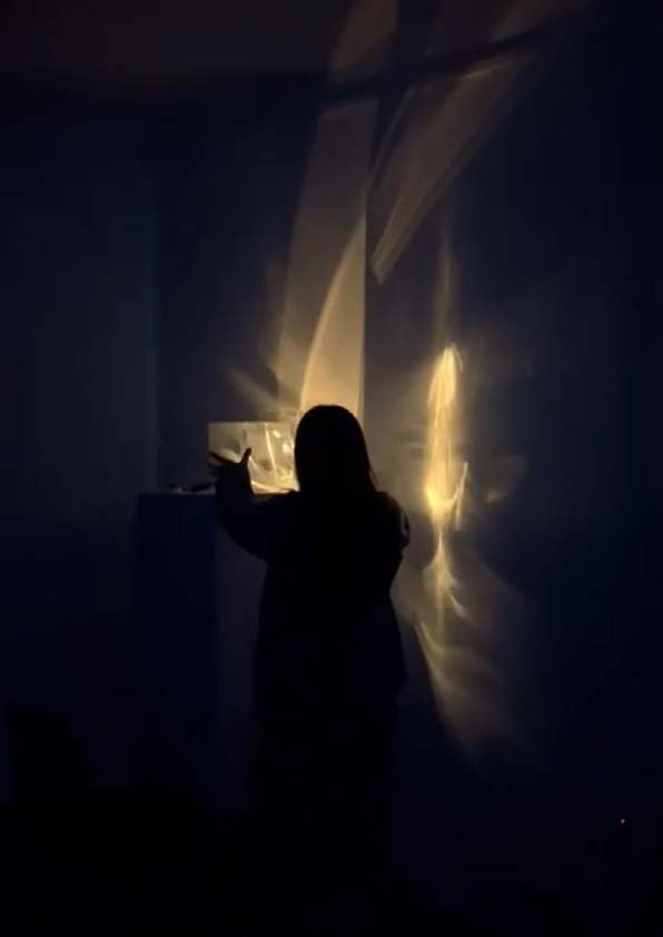 The artist standing before the refracted light on the wall.