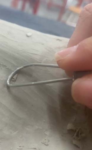 A wire tool shaping the still-wet clay.