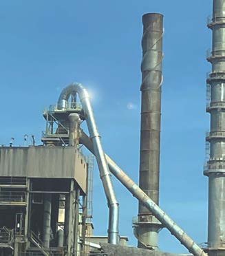 Industrial chimneys against a flat blue sky.