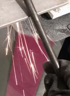 Sparks from the grinder against the raw cast.